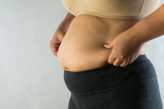 woman's hand holding excessive belly fat