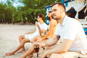 Young people enjoying summer vacation sunbathing drinking at beach bar