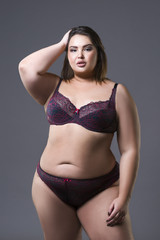 Plus size fashion model in underwear, young fat woman on gray background, overweight female body