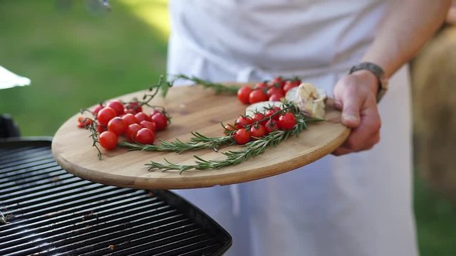 Cook takes the grilled garlic from the grill.