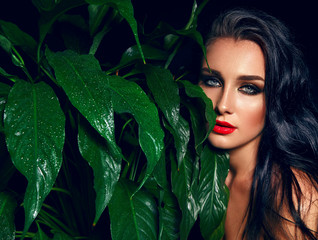 Beautiful sultry tanned girl with bright make-up and dark hair. She is in the jungle among the...