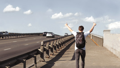 Young man with a backpack walking on a bridge