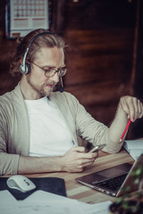 Freelancer talking by phone using handsfree headset. Man at home office speaking on mobile phone...