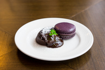 Chocolate lava cake with macaroon and peppermint on white plate, selective focus