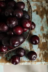 Ripe plums in a basket on a wooden background. Macro photo.