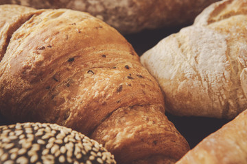 Bread background, closeup of white and black loaves and croissan
