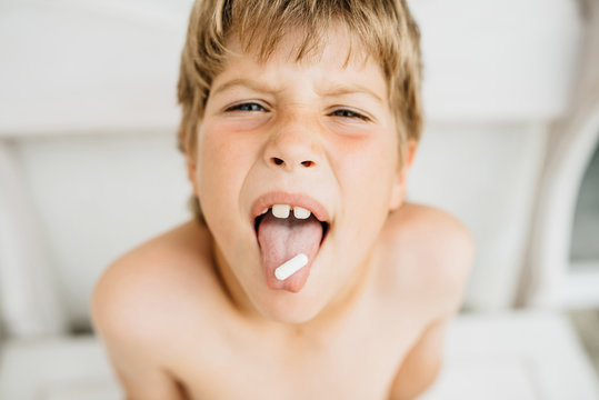 The boy holds the tablet on the tongue