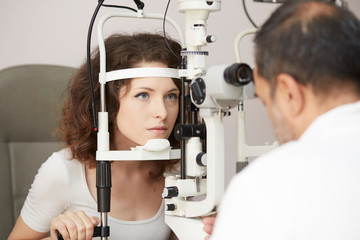 Fototapeta na wymiar pretty young woman having her eyes examined by an eye doctor