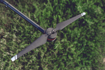 Obraz premium Black drone arm with small engine and air screw on the top. Drone standing on the grass.