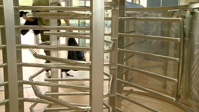 Turnstile. Revolving exit, door. People pass a turnstile at the bus, railway, subway station. Business building. Security metal detector. 3