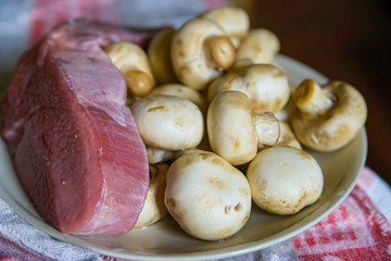 Fresh white mushrooms and raw meat on plate