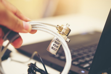 Hand on computer cable lock on leather,computer security concept, internet privacy, Cyber safety concept, locked chain on laptop computer keyboard background, Security shot for the digital age