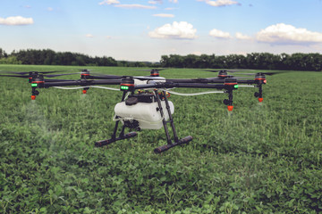 Agriculture drone fly to sprayed fertilizer on the green fields. drone flying with blue sky.