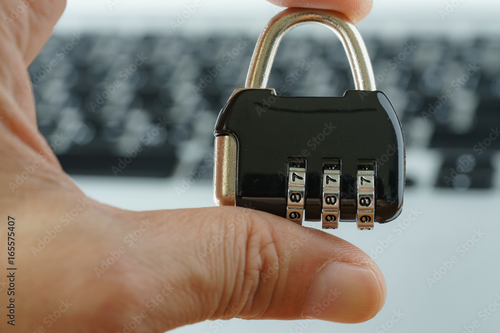Aufkleber computer security concept, with hand holding combination lock pad with the background of computer ke