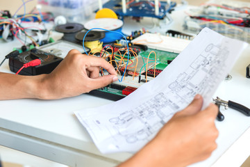 Male electrician reading diagram.Young energetic male tech or engineer repairs electronic equipment...