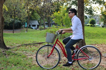 Fototapeta premium Portrait of hipster guy is riding a bicycle in nature summer park.