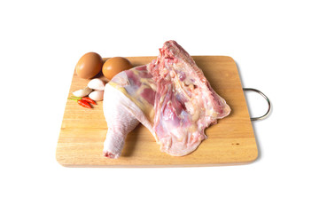 Fresh whole raw chicken with eggs, garlic and pepper on wooden chopping board isolated on white background.