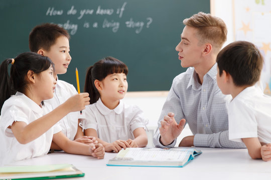 Male teacher helping students study in classroom