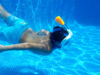 El niño esta buceando en la piscina con easy breath mask