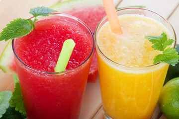 Smoothies from orange and tangerine and smoothie from watermelon with mint on wooden background