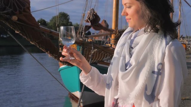 Young woman relaxing on embankment and drinking wine