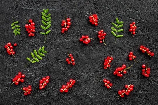 Berry pattern. Red currant and leaves on black table background top view