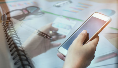young brunette looking at credit card and smartphone in bright living room