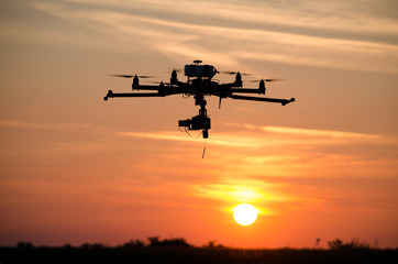 Fototapeta na wymiar Professional drone flying at the sunset on red sky