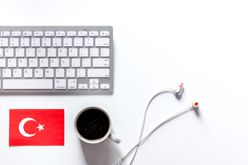 Learning languages online. Turkish. Headphones and keyboard on white table background top view copyspace