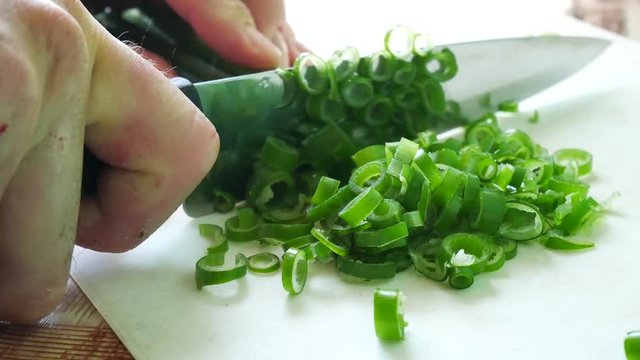 The knife slicks green onions. Cooking the salad.