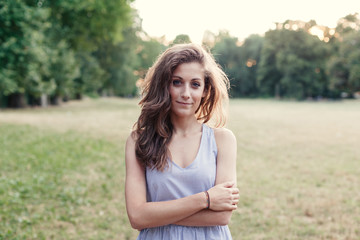Portrait of beautiful young woman in park at sunset during summer