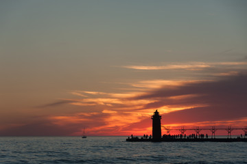 Dramatic view of lighthouse and pier at sunset.