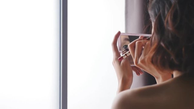 Young woman applying eyeliner. 