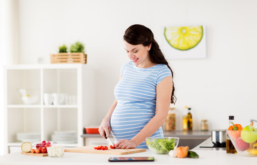 Obraz na płótnie Canvas pregnant woman cooking vegetables at home