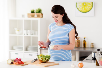 pregnant woman cooking vegetable salad at home