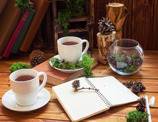 Cups with tea or coffee on a wooden background. Morning breakfast with cones and a book