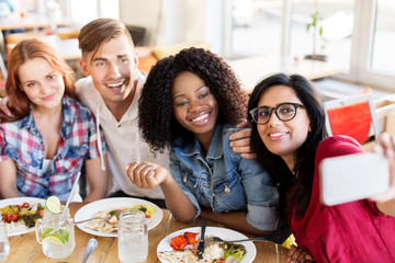 friends eating and taking selfie at restaurant