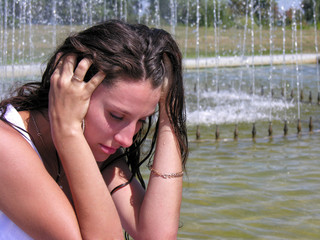 young woman cooling near the fountain in hot day 