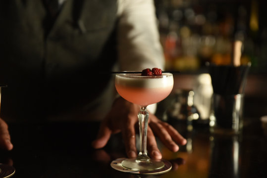 Bartender serving a pink cocktail 