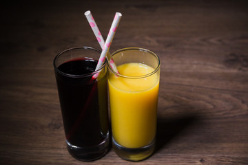 Two fresh glasses of juice with a straw
