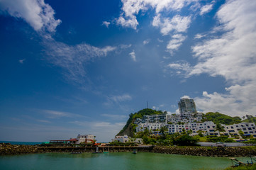 Beautiful rocky beach with a buildings structure of hotels behind in a beautiful day in with sunny weather in a blue sky in Same, Ecuador