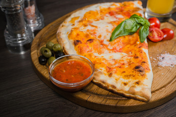 Hot piece of pizza with melted cheese on a rustic wooden table