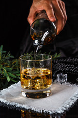 whiskey poured into a glass with ice using a steel dispenser