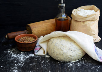 Preparation of homemade bread from whole wheat flour and flax seeds on a dark wooden background. Copy space. Photographing with natural light