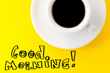 Coffee espresso in small white ceramic cup on yellow vibrant background. Text Good Morning. Minimalism Food Morning Energy Concept.