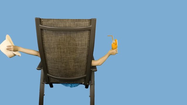 Young caucasian girl sitting on chair and drinking orange juice cocktail through straw.