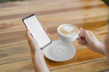 Business hand with mobile phone and latte art coffee .