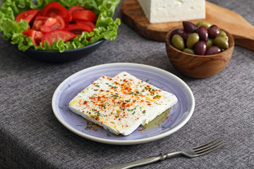 formaggio bianco con spezie pomodori e olive su tavolo grigio