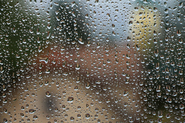 Rain drops on window with house and church in background