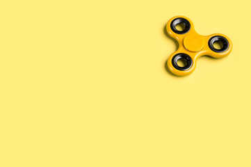 Yellow fidget spinner background template with copy space. Popular kids stress and anxiety relief toy in the top right corner.